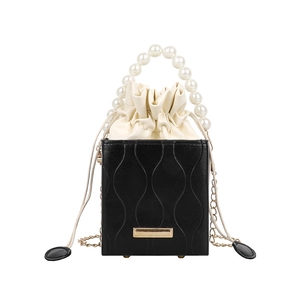 Minimalist pearl handle bucket bag with black embossed texture and gold chain strap