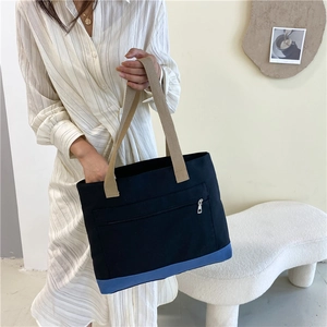 Minimalist black canvas tote bag with blue base and zipper pocket for daily commute