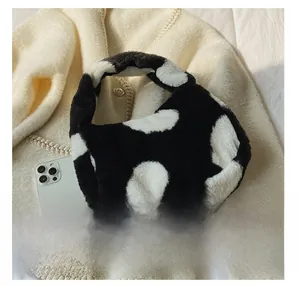 Vue détaillée du sac à main en fausse fourrure motif vache sur fond en tricot chaud