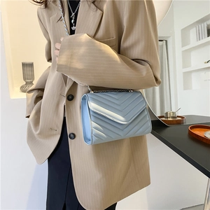 Sac à bandoulière matelassé bleu clair avec chaîne argentée porté à l'épaule