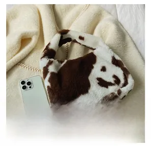 Detailed view of plush cow print handbag next to phone for size comparison