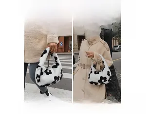 Detail of plush tote bag with black flower pattern showing hand-carry and shoulder styles