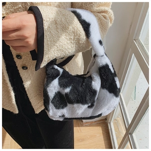 Detail of soft black and white floral plush shoulder bag with cow print texture