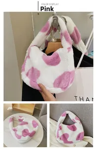 Détail d'un sac en peluche à motif de cœur rose et blanc avec bandoulière large