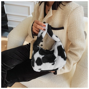 Detailed cow print plush tote bag with fuzzy texture shown as a stylish handheld accessory