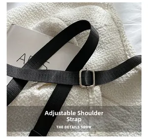 Detail view of the adjustable black nylon shoulder strap on a white tweed handbag