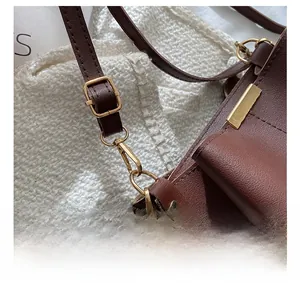 Détail du fermoir mousqueton doré et de la bandoulière réglable sur le sac en cuir brun