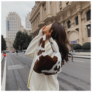 Close-up of fluffy faux fur tote bag with stylish cow print in street style setting
