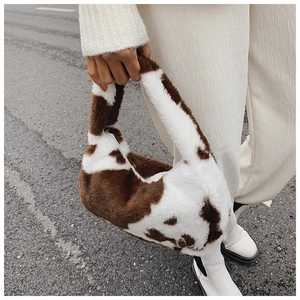 Close-up of plush cow print tote bag with soft texture and white zipper closure