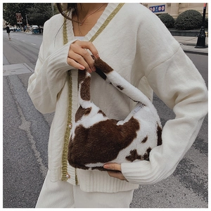 Close-up of cow print plush shoulder bag showing fluffy faux fur texture and crescent shape