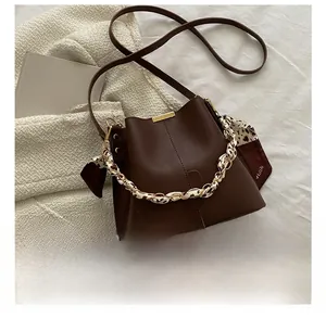 Détail du sac seau en cuir marron foncé avec anse en soie et boucle dorée