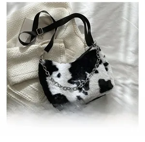 Detail showing plush cow print shoulder bag with silver metal chain and wide strap