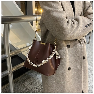 Détail du sac seau en cuir marron foncé avec foulard léopard porté sur un manteau