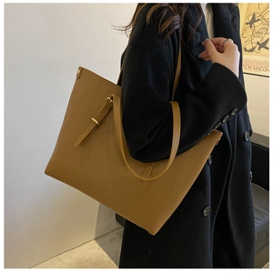 Detail view of large brown leather tote bag with elegant golden buckle and slim shoulder strap