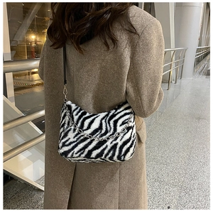 Detail of zebra pattern plush shoulder bag with silver chain strap on a model