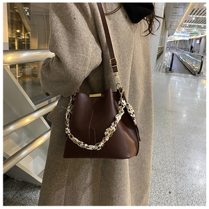 Détail du sac seau en cuir marron foncé avec poignée foulard léopard et chaîne dorée