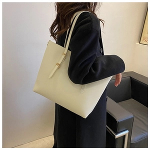 Detail of minimalist cream tote bag with gold buckle on shoulder strap worn by model