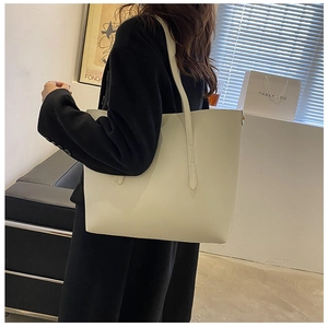 Detail of a cream large tote bag worn over a black blazer for a modern work look