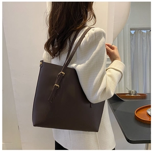 Detail of dark brown tote bag featuring golden metal adjustable buckle on shoulder strap