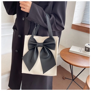 Detail of the oversized black leather bow on an off-white chic tote bag for women