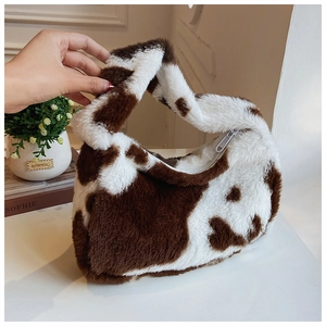 Close-up of cow print plush tote bag with soft faux fur texture and zipper closure