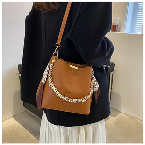 Détail du sac seau en cuir marron avec chaîne en foulard léopard et fine bandoulière