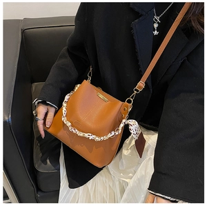 Sac seau en cuir marron caramel avec foulard léopard porté avec une veste noire