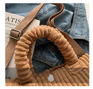 Detail of a brown corduroy handbag showing spiral textured handles and canvas strap