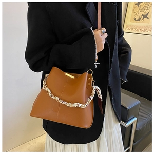Détail d'un sac seau fauve avec bandoulière chaîne et foulard en soie sur veste