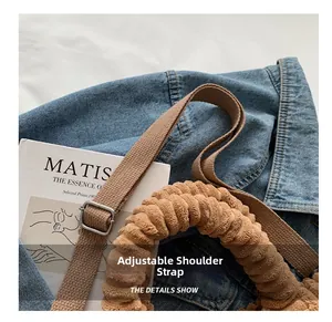 Detail of adjustable brown fabric strap and plush corduroy handle with silver metal buckle