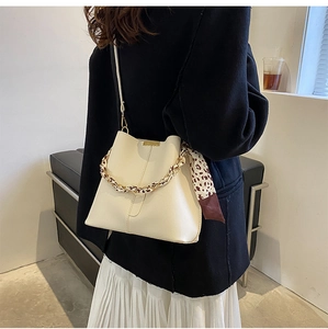Détail du sac seau crème avec poignée chaîne dorée et foulard en soie léopard