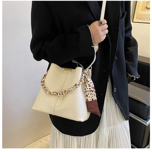 Détail du sac seau crème avec poignée chaîne foulard léopard et texture cuir grainé