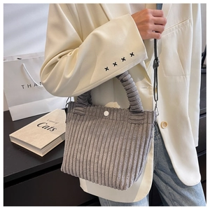 Detail of grey corduroy tote bag featuring a stylish scrunchie handle and white button