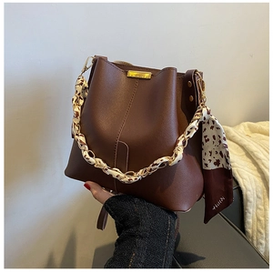 Détail du sac seau vintage en cuir marron avec foulard léopard et boucle dorée