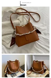 Détail d'un sac seau marron avec chaîne ornée d'un foulard floral et accents en métal