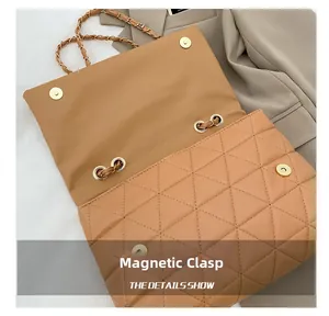 Gros plan sur le fermoir magnétique d'un sac cabas matelassé avec chaîne dorée