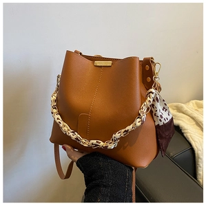 Détail du sac seau marron caramel avec anse en chaîne ornée d'un foulard léopard