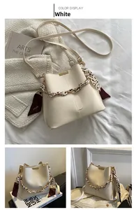 Détail du sac seau crème avec chaîne enroulée d'un foulard léopard et accents en soie