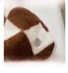 Detail of plush checkered handbag with soft texture and metallic logo button