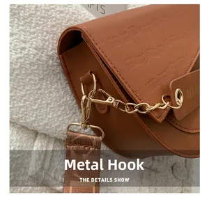 Detailansicht der braunen Kroko-Ledertasche mit goldenem Metallhaken und Gurt