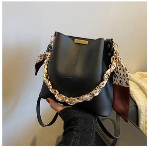Détail du sac seau noir avec poignée en chaîne dorée et foulard à imprimé léopard