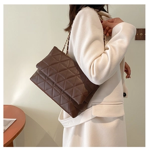 Détail du sac à chaîne matelassé marron foncé avec coutures triangulaires et chaîne dorée