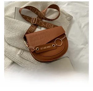 Detailansicht einer braunen Vintage-Satteltasche mit Goldkette und Web-Schultergurt
