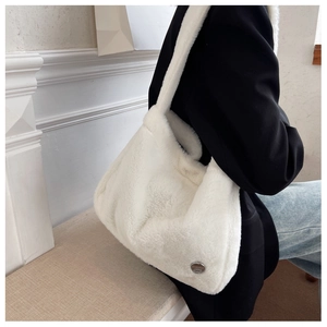 Detailed view of white plush faux fur shoulder bag with wide strap and metal logo