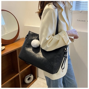 Detail of embossed black tote bag with plush charm and stylish tassel side zipper