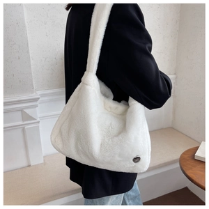Detail of white plush hobo bag with soft faux fur texture and silver metal logo