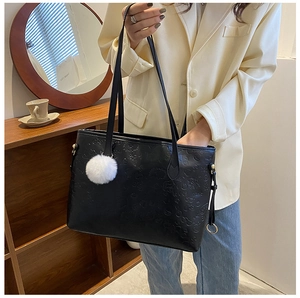 Detail of black PU leather tote bag with cartoon embossed pattern and white pompom charm