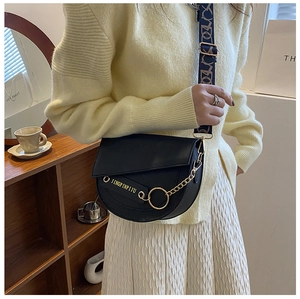 Detailaufnahme der schwarzen Vintage-Satteltasche mit Goldkette und gewebtem Riemen