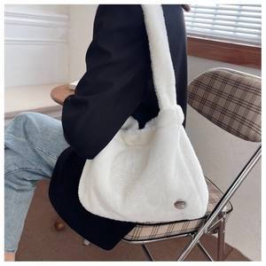 Detailed view of large white plush hobo bag with wide shoulder strap worn by a model