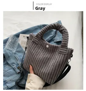 Detail of grey corduroy tote bag with ruffled handle and textured vertical stripes